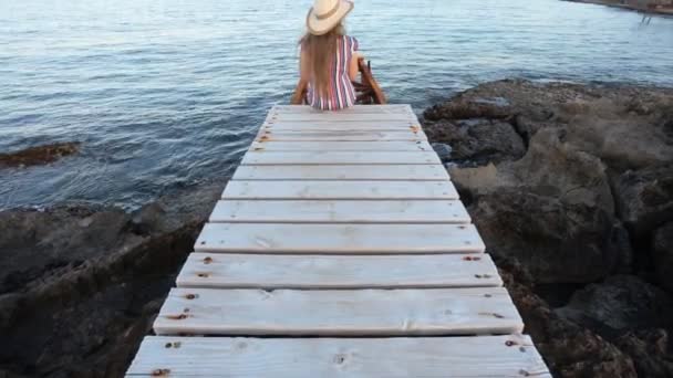 Jonge vrouw zittend op de pier — Stockvideo