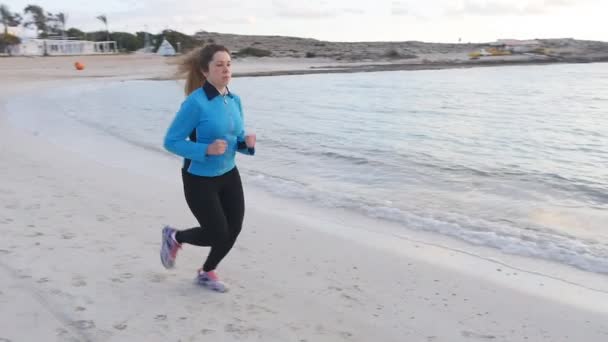 Жінка біжить на пляжі на заході сонця — стокове відео