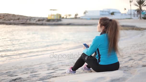 Belle femme de fitness assis et reposant sur la mer — Video