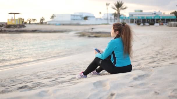 Kvinna som sitter på stranden — Stockvideo