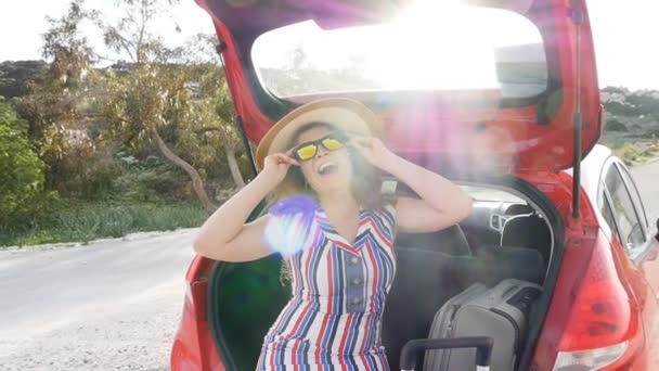 Young woman with suitcase in car trunk — Stock Video