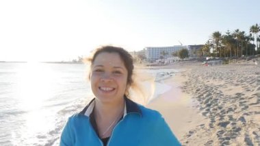 Kadın Jogger batımında sahilde gülümseyerek.