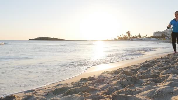 Fiatal nő fut a strandon naplementekor — Stock videók