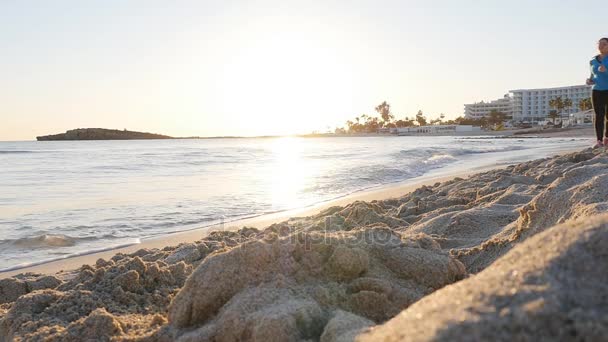 Junge Frau läuft bei Sonnenuntergang am Strand — Stockvideo