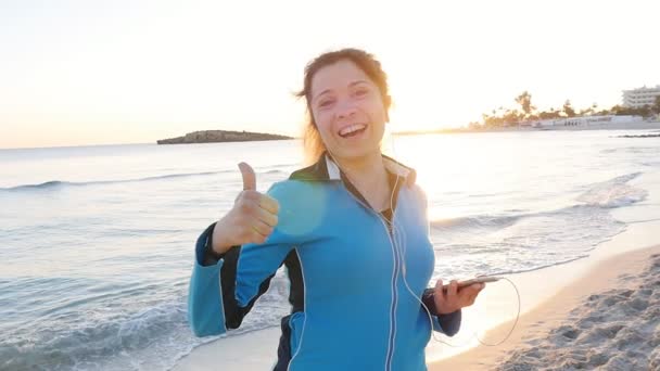 Sorrindo feminino fitness mostrar polegares para cima na praia — Vídeo de Stock