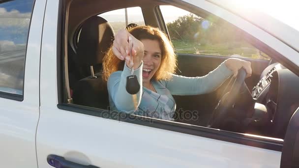 Молодая женщина показывает ключ к новой машине — стоковое видео