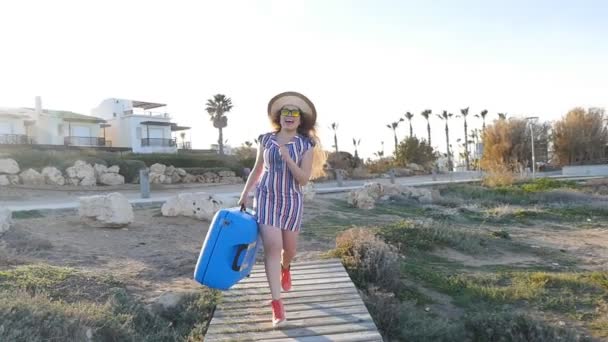 Une jeune femme avec un chapeau court avec une valise dans les mains — Video