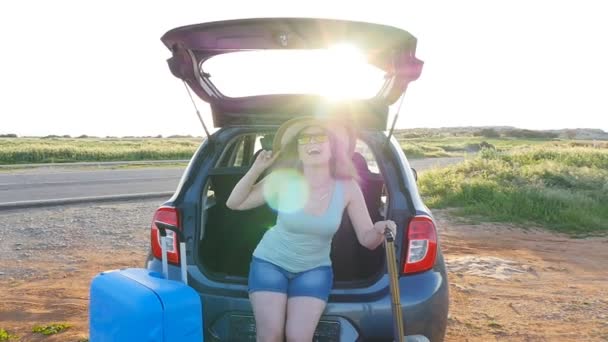 Young woman sits in the trunk of a car. Travel concept — Stock Video