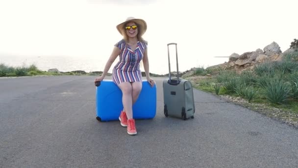 Mujer joven feliz de vacaciones en un sombrero con una maleta — Vídeos de Stock