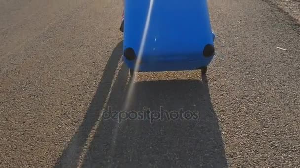 Young woman traveler in a hat runs with a blue suitcase — Stock Video