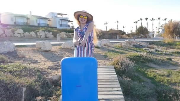 Счастливая молодая женщина на отдыхе в шляпе с чемоданом — стоковое видео