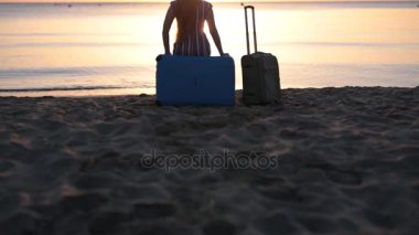 Bavul bir plajda üzerinde oturan genç kadın