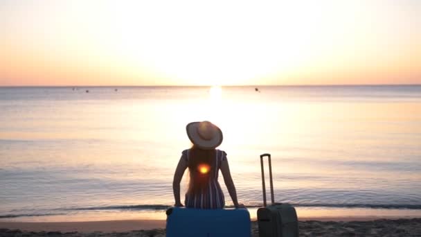 Junge Frau sitzt auf Koffer am Strand — Stockvideo