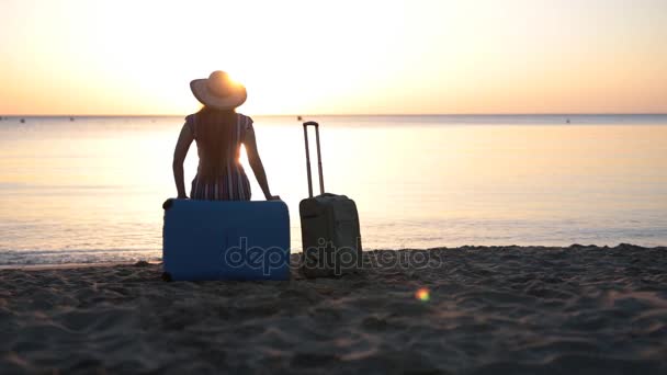 Een jonge vrouw zit op een koffer in de buurt van de zee — Stockvideo