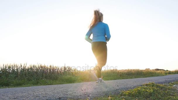 Junge Läuferin läuft auf der Sonnenaufgangsstraße. Fitnesskonzept — Stockvideo