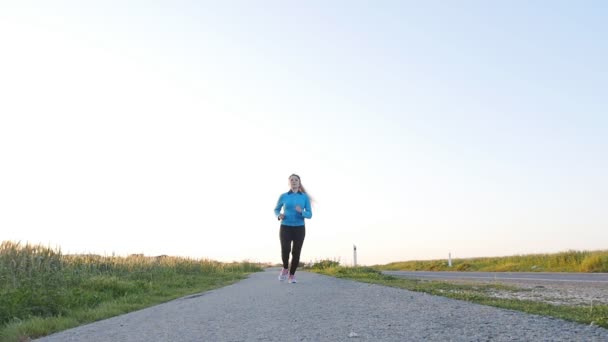 Молодая бегунья бежит по дороге восхода солнца. Фитнес-концепция — стоковое видео