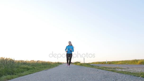 Mladá žena běžec běží na východ silnice. Fitness koncept