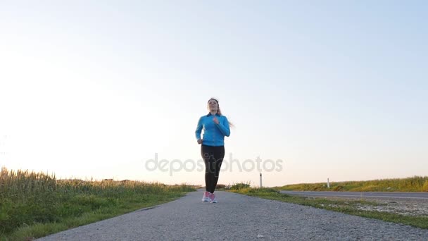 Ung kvinna löpare kör på sunrise road. Fitness-konceptet — Stockvideo