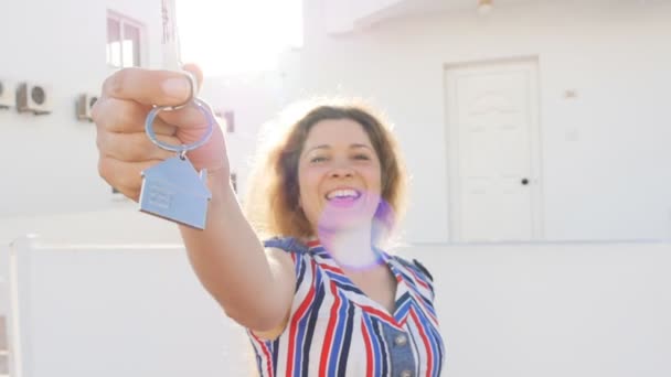 Attraktiv ung kvinna håller ned tangenter samtidigt står utomhus mot nya huset. — Stockvideo