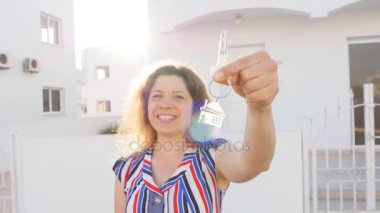 Yeni ev karşı açık ayakta iken anahtarları tutan çekici genç kadın.