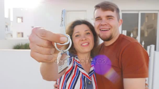 Šťastný mladý pár stojící venku drží klíč k jejich nového domu — Stock video