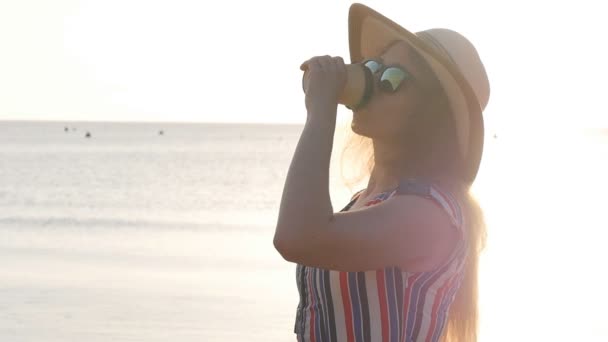 Fiatal nő iszik kávé a strandon — Stock videók