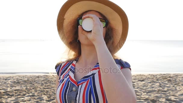 Ung kvinna dricker kaffe på stranden — Stockvideo