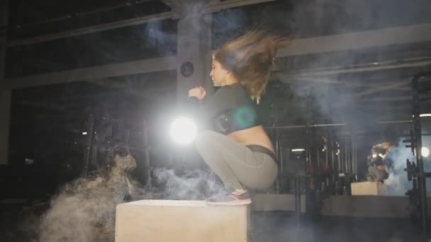 Jeune femme sportive sautant par-dessus des boîtes dans une salle de gym cross-training — Video