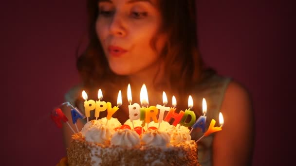 Jovem mulher soprando velas em um bolo de aniversário — Vídeo de Stock