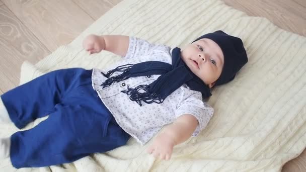 Niño bonito está acostado en la alfombra blanca — Vídeo de stock