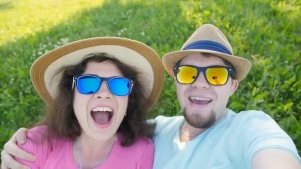 Jovem casal amoroso fazendo selfie enquanto deitado na grama — Vídeo de Stock