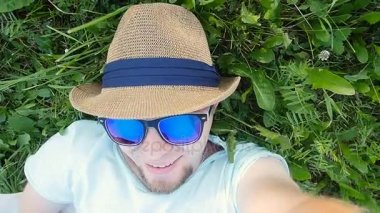 Mutlu bir adam selfie alarak bir parkta çim üzerinde yalan
