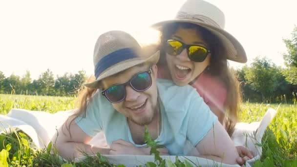 Young couple lying down in grass and having fun — Stock Video