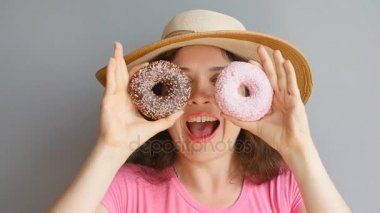 Genç kadın gözleri karşı donuts tutarak ve gülümseyen