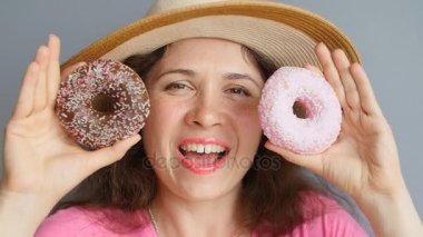 Genç kadın gözleri karşı donuts tutarak ve gülümseyen