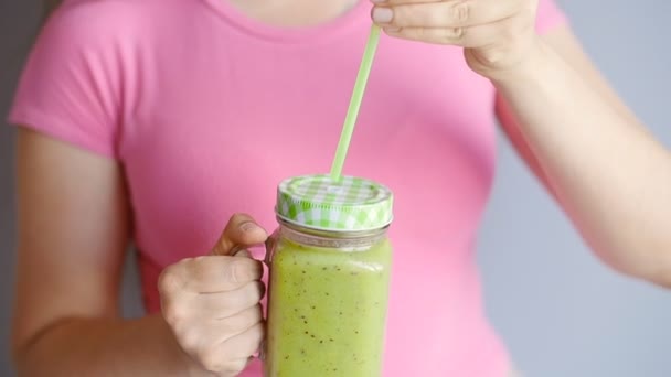En lycklig kvinna håller en grön smoothie i händerna — Stockvideo