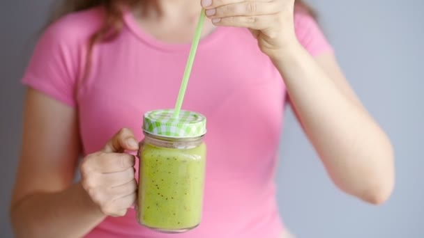 Een gelukkige vrouw houdt een groene smoothie in haar handen — Stockvideo