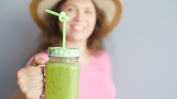 Een gelukkige vrouw houdt een groene smoothie in haar handen — Stockvideo