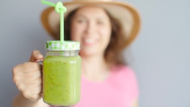 Een gelukkige vrouw houdt een groene smoothie in haar handen — Stockvideo