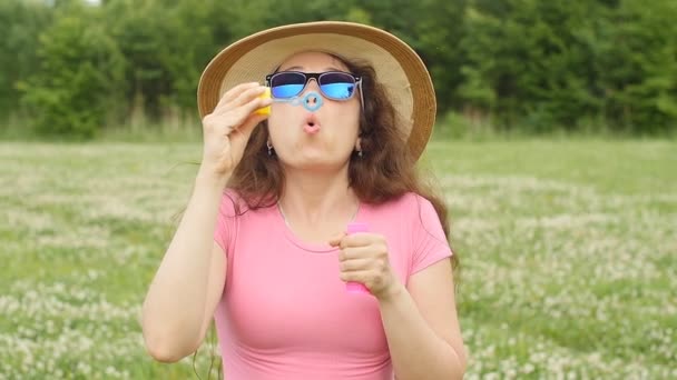 Young woman blowing bubbles outdoors — Stock Video