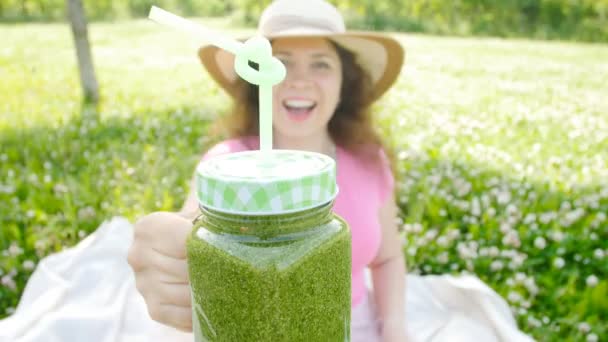 Young woman with green vegetable smoothies in the park — Stock Video
