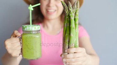 Yeşil smoothie ve kuşkonmaz tutan kadın