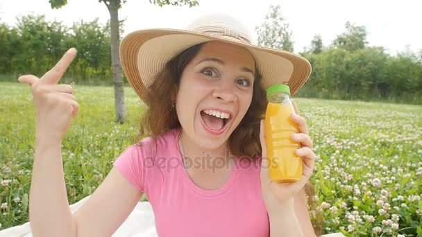 Jovem mulher bebendo suco em um parque — Vídeo de Stock