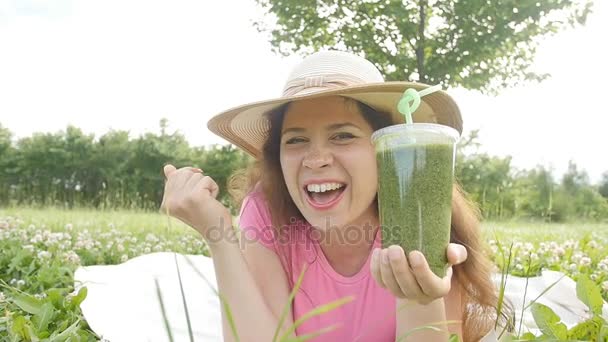 젊은 여자는 공원에 재미가 있고 녹색 스무디를 마셔 — 비디오