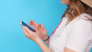 Mavi renk arka plan üzerinde cep telefonu kullanan genç kadın