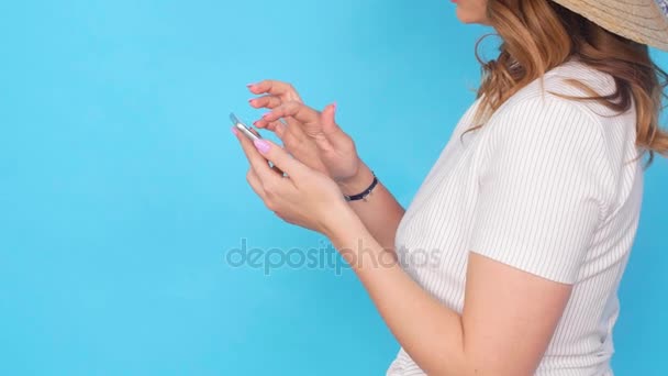 Mladá žena pomocí mobilního telefonu na modrou barvu pozadí — Stock video