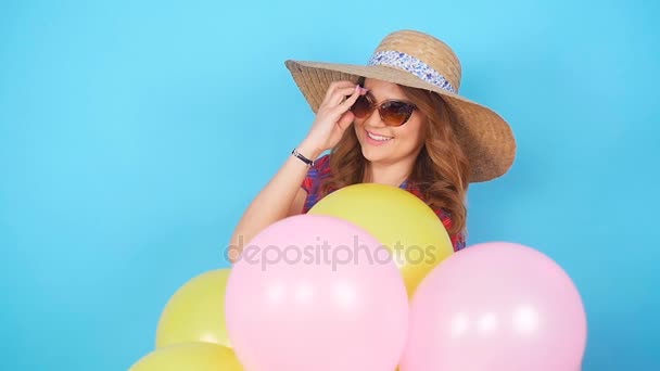 Mujer feliz con un aire colorido globos se divierte sobre un fondo azul — Vídeos de Stock