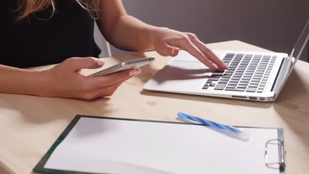 Bir kız bir smartphone olan bir bilgisayar arkasındaki ofiste çalışıyor — Stok video