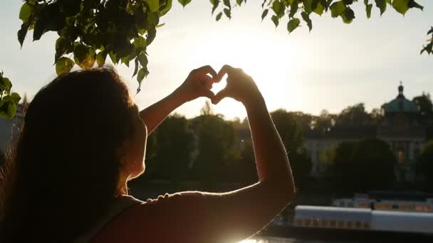 Молодая женщина делает символ очага на закате — стоковое видео