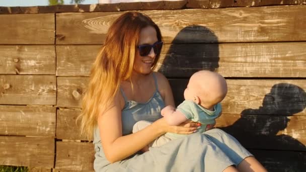 Feliz madre y bebé sentado en la hierba — Vídeos de Stock